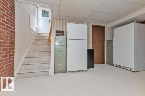 Carpeted flooring extending to the staircase featuring a wood handrail - 11415 56 Avenue Nw, Edmonton, AB 