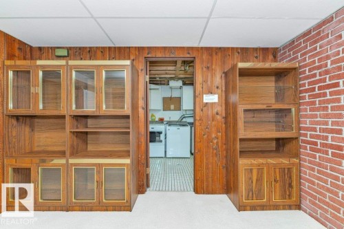 Wood-paneled wall with built-in cabinetry featuring glass-front doors - 11415 56 Avenue Nw, Edmonton, AB 