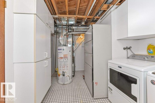 Utility room featuring extensive white cabinetry, a tiled floor, and exposed ceiling joists - 11415 56 Avenue Nw, Edmonton, AB 