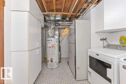 Utility room featuring extensive white cabinetry, a tiled floor, and exposed ceiling joists - 