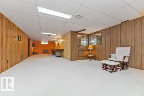 Expansive room featuring light-toned carpeting and wood paneling on the walls - 11415 56 Avenue Nw, Edmonton, AB 