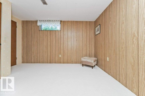 Spacious room featuring light wood-panel walls and white carpeting - 11415 56 Avenue Nw, Edmonton, AB 