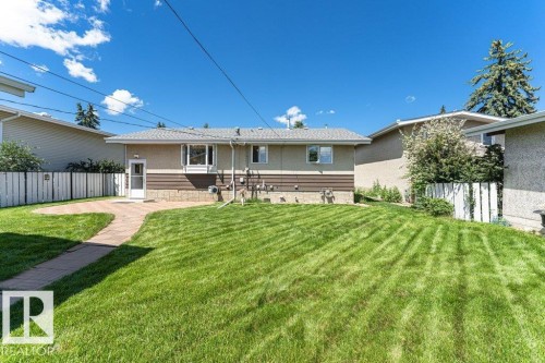 Spacious backyard featuring an expansive lawn area and a paver patio - 11415 56 Avenue Nw, Edmonton, AB 