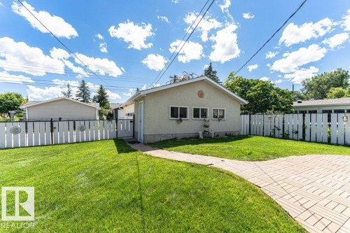 Expansive green lawn with a paver stone pathway and white picket fencing - 11415 56 Avenue Nw, Edmonton, AB 