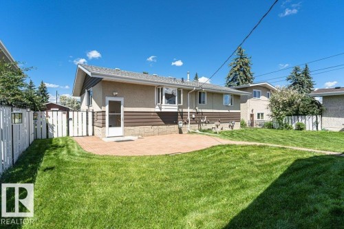 Expansive rear yard featuring a curved paver patio and verdant lawn - 11415 56 Avenue Nw, Edmonton, AB 