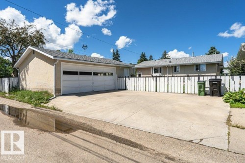 Detached garage featuring a white panel door with windows, stucco exterior, and a shingled roof - 11415 56 Avenue Nw, Edmonton, AB 