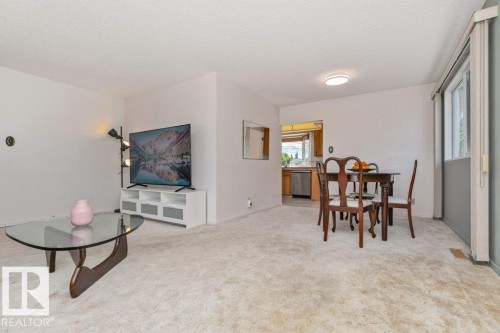 Carpeted living area with white walls and a window overlooking exterior elements - 11415 56 Avenue Nw, Edmonton, AB 