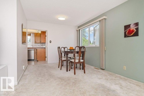 Dining area featuring light-toned carpeting, a window with vertical blinds, and a neutral color palette - 11415 56 Avenue Nw, Edmonton, AB 