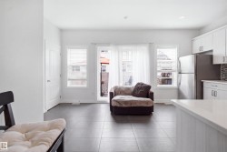 Spacious open-concept room with tile flooring, white walls, and multiple windows - 