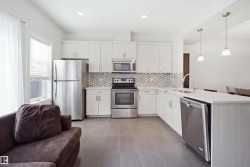 Stainless steel appliances, white cabinetry, mosaic tile backsplash, recessed lighting, and pendant lighting - 