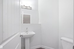 Pedestal sink with chrome faucet, mirror, wall-mounted light fixture, and white painted walls - 