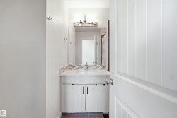 Vanity with a single basin, tiled backsplash, and wall-mounted light fixture - 