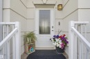 White entry door with decorative glass insert, wall-mounted exterior light fixture, and white railings - #22 723 172 Street Sw, Edmonton, AB 