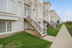 Exterior features include a private entry staircase, lower-level windows, and a concrete walkway - 