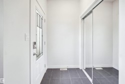 Entryway featuring a white door with decorative glass, a smart lock, dark tile flooring, and a mirrored sliding closet door - 