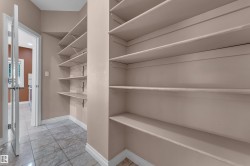 Spacious pantry featuring extensive built-in shelving, tile flooring, and neutral wall tones - 