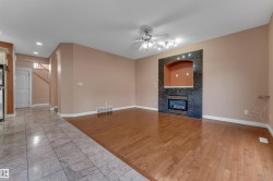 Hardwood flooring, tiled flooring, built-in fireplace with black surround, ceiling fan with track lighting, arched entryway - 