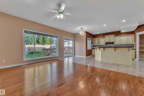 Hardwood flooring extending to a tiled kitchen area, featuring a multi-pane window and sliding glass door - 3455 29 Street Nw, Edmonton, AB 