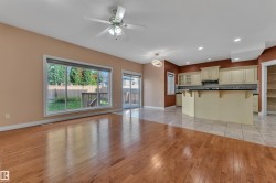 Hardwood flooring extending to a tiled kitchen area, featuring a multi-pane window and sliding glass door - 
