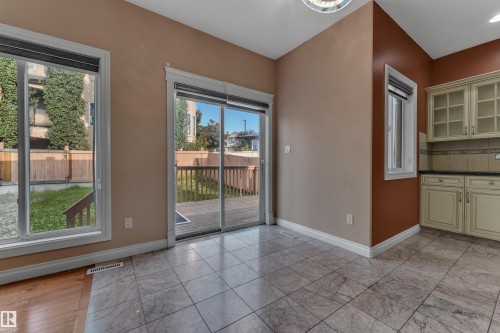 Tile flooring, sliding glass door, white window trim, wood-finish deck, built-in cabinetry with glass inserts - 3455 29 Street Nw, Edmonton, AB 