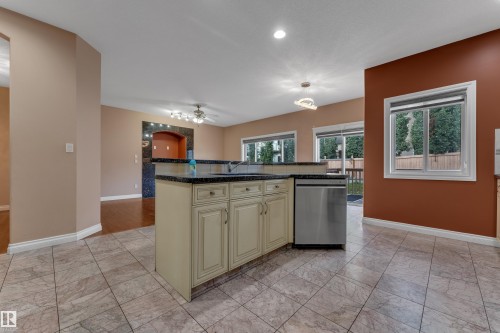 Kitchen island with light-toned cabinetry, dark countertops, and a stainless steel dishwasher - 3455 29 Street Nw, Edmonton, AB 