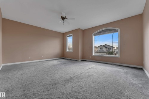 Spacious interior featuring a large arched window, additional sash windows, and a ceiling fan - 3455 29 Street Nw, Edmonton, AB 
