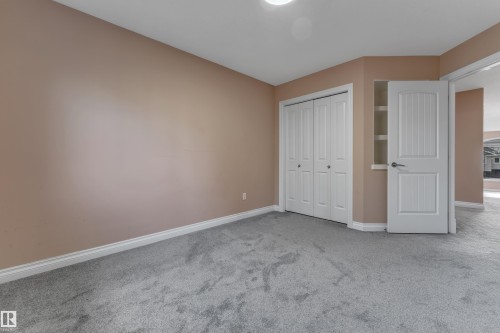 Plush grey carpeting, painted walls, white bi-fold closet doors, and built-in shelving - 3455 29 Street Nw, Edmonton, AB 