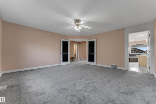 Spacious room with plush gray carpeting, light peach wall paint, and a built-in ceiling fan with lighting - 3455 29 Street Nw, Edmonton, AB 