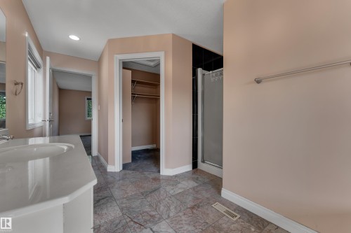 Double vanity with integrated sinks, patterned tile flooring, walk-in shower with black tile surround, and recessed lighting - 3455 29 Street Nw, Edmonton, AB 