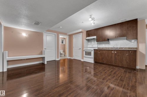 Full kitchen with wood-finish cabinetry, white appliances, and a tiled backsplash - 3455 29 Street Nw, Edmonton, AB 