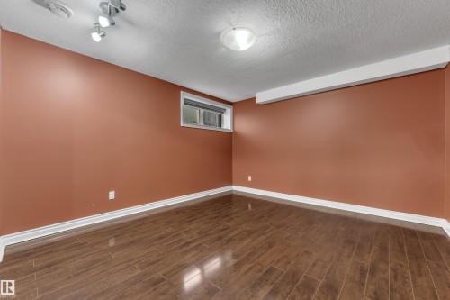 Wood-finish flooring with white baseboards, a single window, and overhead flush mount lighting - 3455 29 Street Nw, Edmonton, AB 