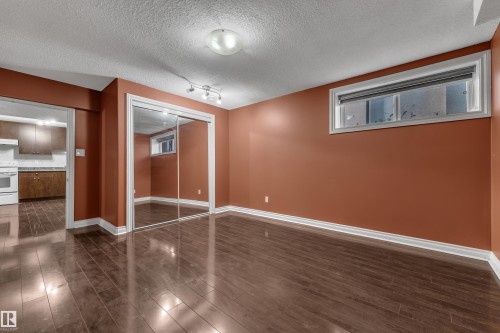 Wood-finish flooring, mirrored sliding closet doors, track lighting, and a recessed window - 3455 29 Street Nw, Edmonton, AB 
