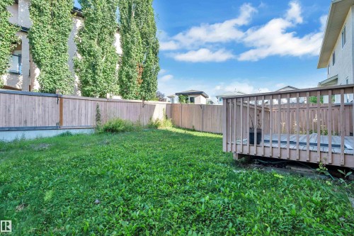 Expansive green space featuring a wooden privacy fence, mature trees, and a wooden deck - 3455 29 Street Nw, Edmonton, AB 