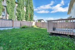 Expansive green space featuring a wooden privacy fence, mature trees, and a wooden deck - 