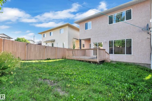 Expansive yard space featuring a wooden privacy fence, a ground-level wood deck, and multiple large windows - 3455 29 Street Nw, Edmonton, AB 