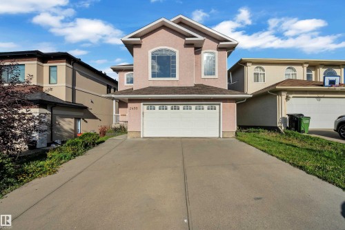 Two-story stucco exterior with arched window accents, attached garage, and paved driveway - 3455 29 Street Nw, Edmonton, AB 
