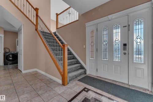 Entry with decorative glass double doors, wood railing, wrought iron balusters, and tiled flooring - 3455 29 Street Nw, Edmonton, AB 