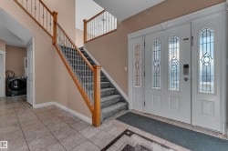 Entry with decorative glass double doors, wood railing, wrought iron balusters, and tiled flooring - 