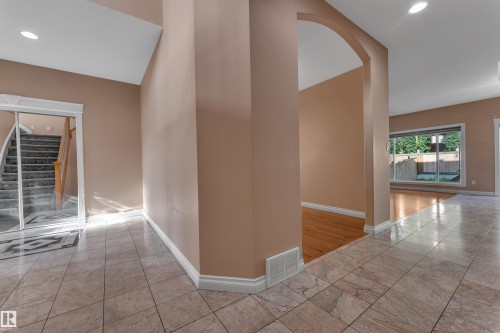 Tiled flooring extending from the entryway, an arched doorway, recessed lighting, and a mirrored closet with a staircase beyond - 3455 29 Street Nw, Edmonton, AB 