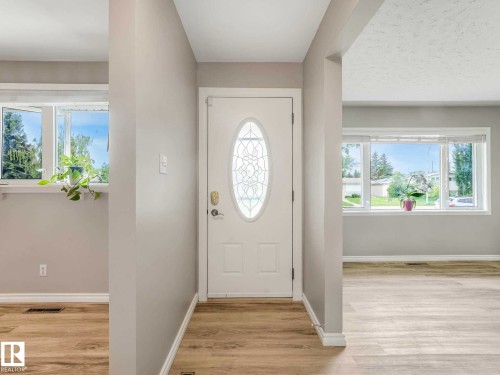 Entryway featuring a white door with an oval leaded glass insert, light wood-finish flooring, and light gray walls - 15916 88B Avenue Nw, Edmonton, AB 