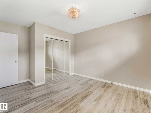Light-colored wood-finish flooring, mirrored closet doors, and a decorative ceiling light fixture - 15916 88B Avenue Nw, Edmonton, AB 