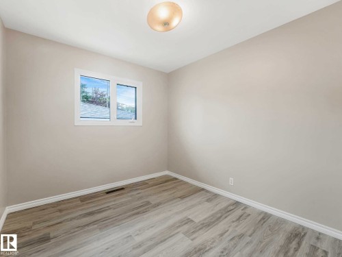 Neutral wall paint, wood-finish flooring, white window trim, and a flush mount ceiling light - 15916 88B Avenue Nw, Edmonton, AB 