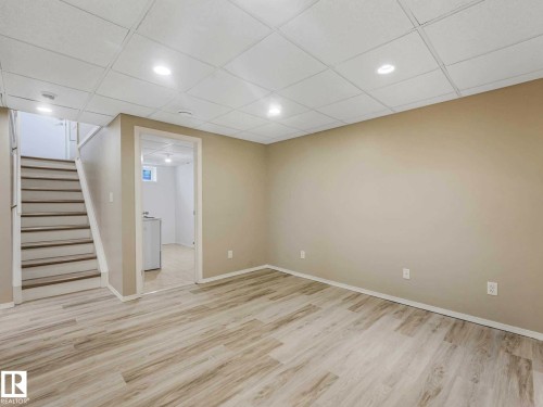 Spacious room featuring wood-finish flooring, recessed lighting, neutral paint, and a drop ceiling - 15916 88B Avenue Nw, Edmonton, AB 