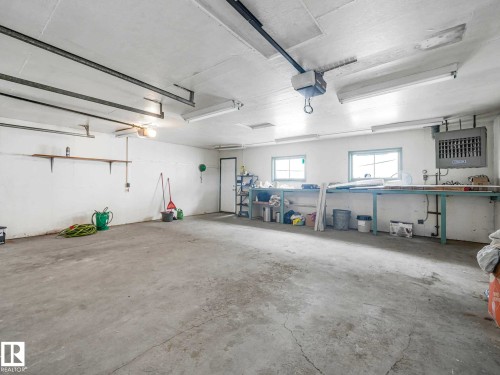 Concrete flooring, wall-mounted shelving, built-in workbench, multiple windows, and overhead lighting - 15916 88B Avenue Nw, Edmonton, AB 
