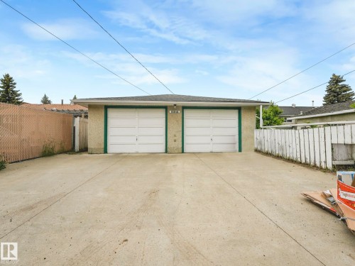 Two-car detached garage with white overhead doors, green trim, and stucco exterior - 15916 88B Avenue Nw, Edmonton, AB 