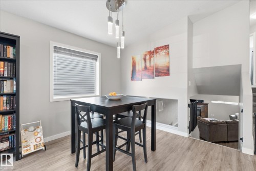 Laminate wood-finish flooring, recessed lower level, and a modern chandelier with pendant lights - 2109 37 Avenue Nw, Edmonton, AB 
