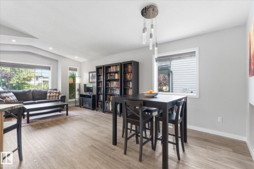Wood-finish flooring throughout, complemented by a contemporary chandelier and recessed lighting - 2109 37 Avenue Nw, Edmonton, AB 
