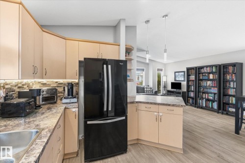 Light-toned cabinetry with under-cabinet lighting, a mosaic tile backsplash, and a double-door refrigerator - 2109 37 Avenue Nw, Edmonton, AB 
