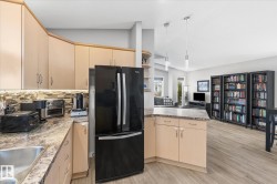 Light-toned cabinetry with under-cabinet lighting, a mosaic tile backsplash, and a double-door refrigerator - 