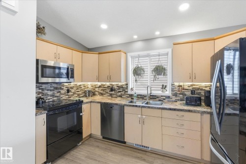 Kitchen featuring light wood-finish cabinetry, stainless steel appliances, a tile backsplash, and recessed ceiling lighting - 2109 37 Avenue Nw, Edmonton, AB 